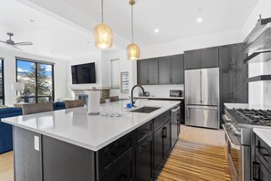 A modern kitchen with a large island, stainless steel appliances, and dark cabinetry. - Sb30s4 (Silverthorne)