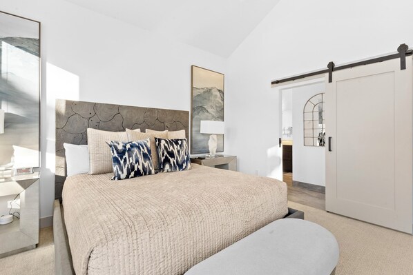A modern bedroom with a large bed, a bedside table, a lamp, and a wardrobe.