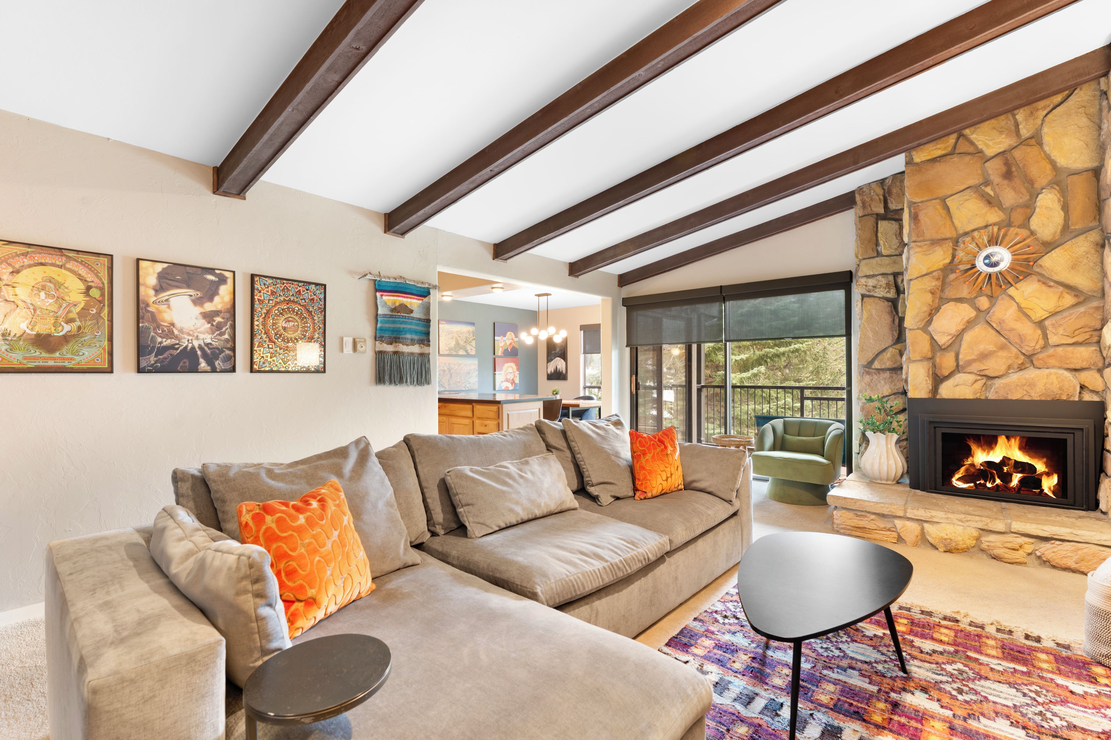 A living room with a stone fireplace, a sofa set, and artwork on the walls.