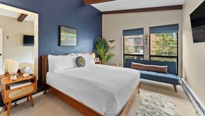 A bedroom with a bed, bedside table, lamp, and a view of the outside. - Lc307ad1 (Dillon)