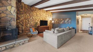 A living room with a stone wall, a fireplace, a sofa, and a television. - Lc307ad1 (Dillon)