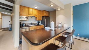 A modern kitchen with wooden cabinets, a central island, and bar stools. - Lc307ad1 (Dillon)