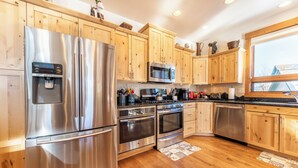 A modern kitchen with stainless steel appliances, wooden cabinets, and a large window. - 94rgrs4 (Silverthorne)