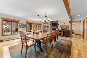 A spacious dining area with a wooden table and chairs, large windows with a view, a chandelier, and a stone fireplace. - E29-4 (Keystone)