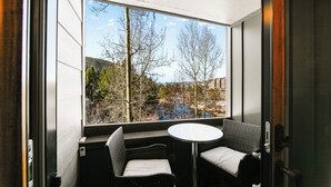 Une pièce avec une grande fenêtre, une table ronde et deux chaises.
