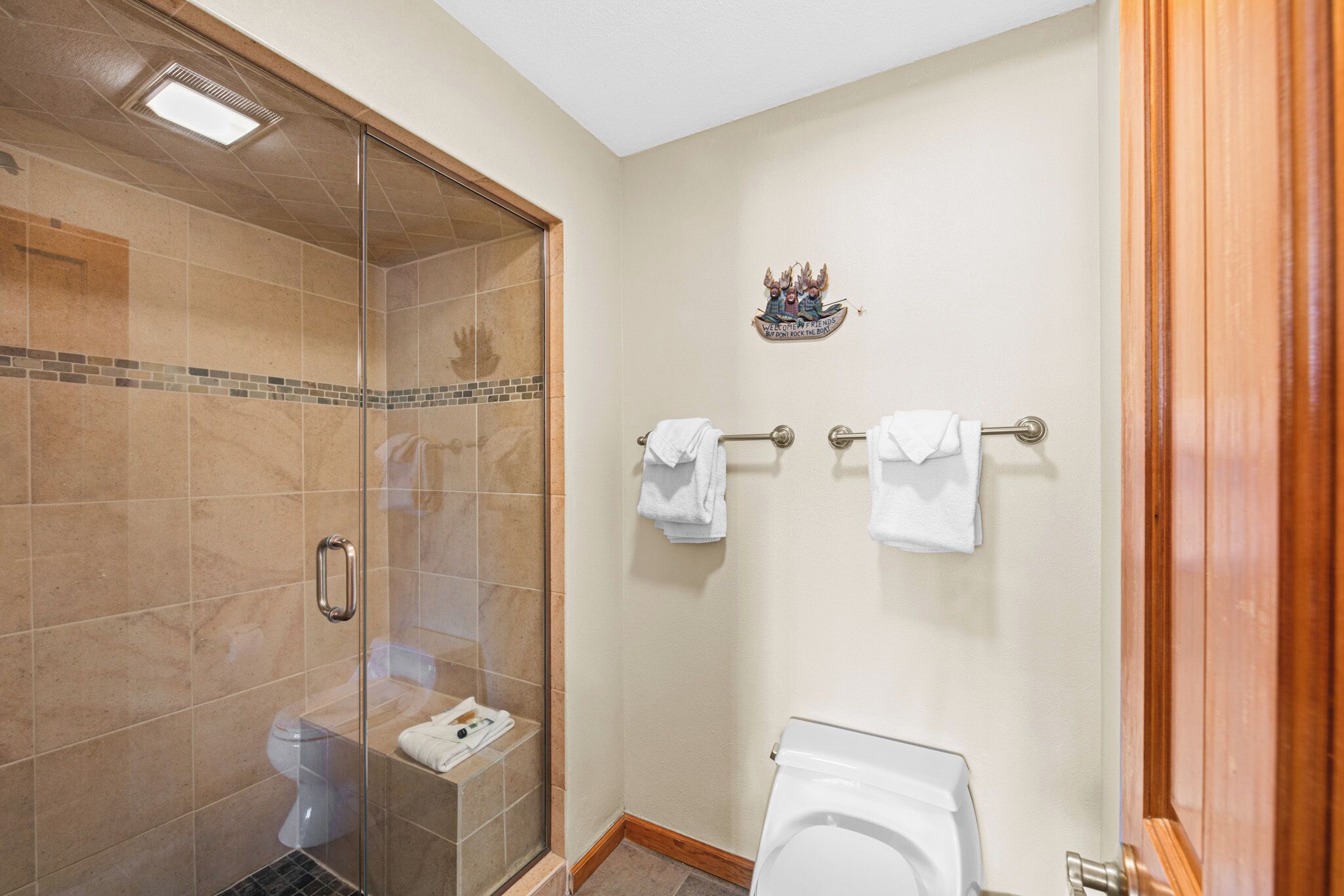 Un baño con ducha de vidrio, inodoro y dos toalleros.
