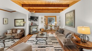 A living room with a fireplace, wooden ceiling beams, and a large window. - Tt1327-3 (Keystone)