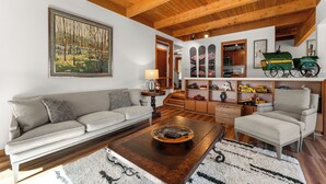 A spacious living room with a high wooden ceiling, a large painting, a sofa, a coffee table, and a chair. - Tt1327-3 (Keystone)
