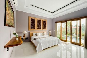 Un dormitorio con una cama, una mesita de noche, una mesa con lámpara y un cuadro en la pared.