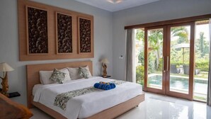 A spacious bedroom with a large bed, a view of a swimming pool through glass doors, and a ceiling with recessed lighting. - Villa d'Alas Ubud (Bali)