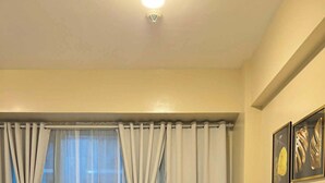 Una habitación de hotel con una cama, cortinas, una ventana y decoración en la pared.