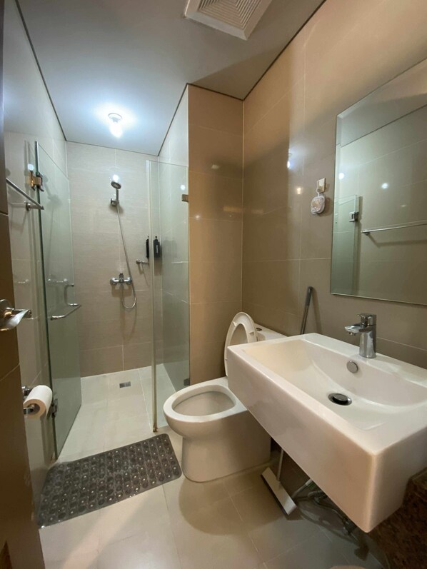 A modern bathroom with a glass shower enclosure, a toilet, and a sink with a mirror.