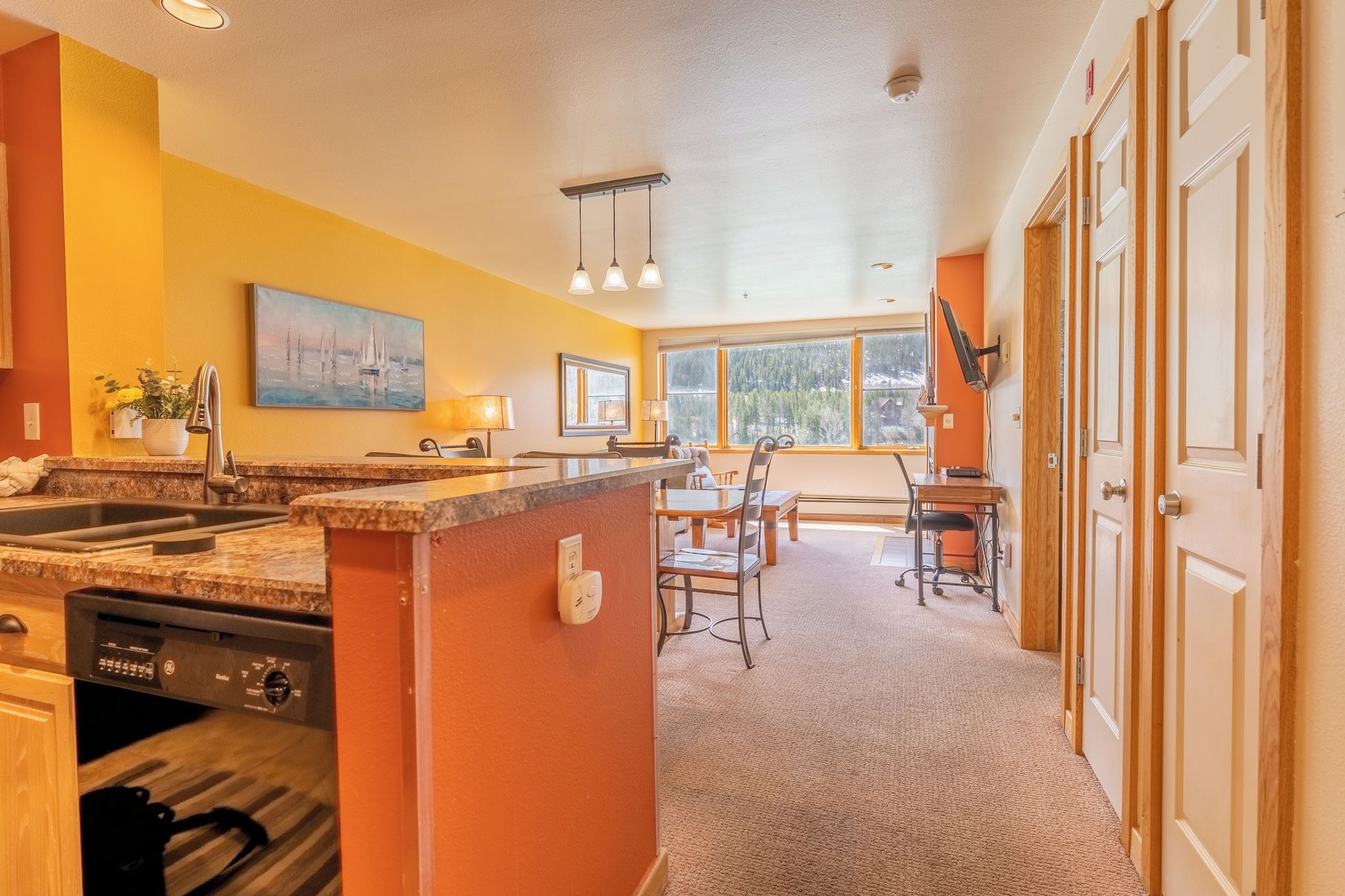 A kitchen with a granite countertop, a dishwasher, and a dining area with a table and chairs.