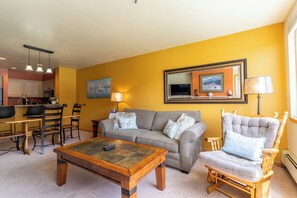 A living room with a sofa, armchairs, a coffee table, and a dining area with chairs and a table.