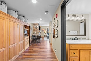 A kitchen with wooden cabinets, a dining area with chairs, and a bathroom with a sink and mirror. - Sj2539-0 (Keystone)