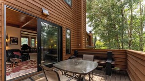 A wooden deck with a glass door leading to an interior space, furnished with a table and chairs, and a bench. - Tt1340-3 (Keystone)