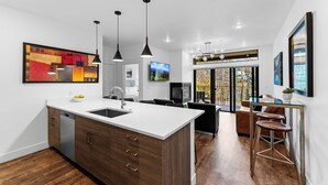 Une cuisine moderne dotée d’un îlot central, de meubles en bois et de luminaires suspendus.