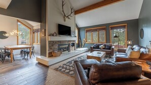 A spacious living room with a fireplace, leather sofas, and a dining area with a wooden table and chairs. - Qs1606-2 (Keystone)
