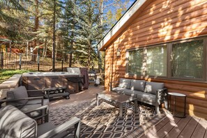 A log cabin with a patio area featuring outdoor furniture, a hot tub, and a grill. - 341bhcs3 (Silverthorne)