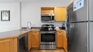 A modern kitchen with stainless steel appliances, wooden cabinets, and a built-in wine rack. - Silver Mill #8220 (Keystone)