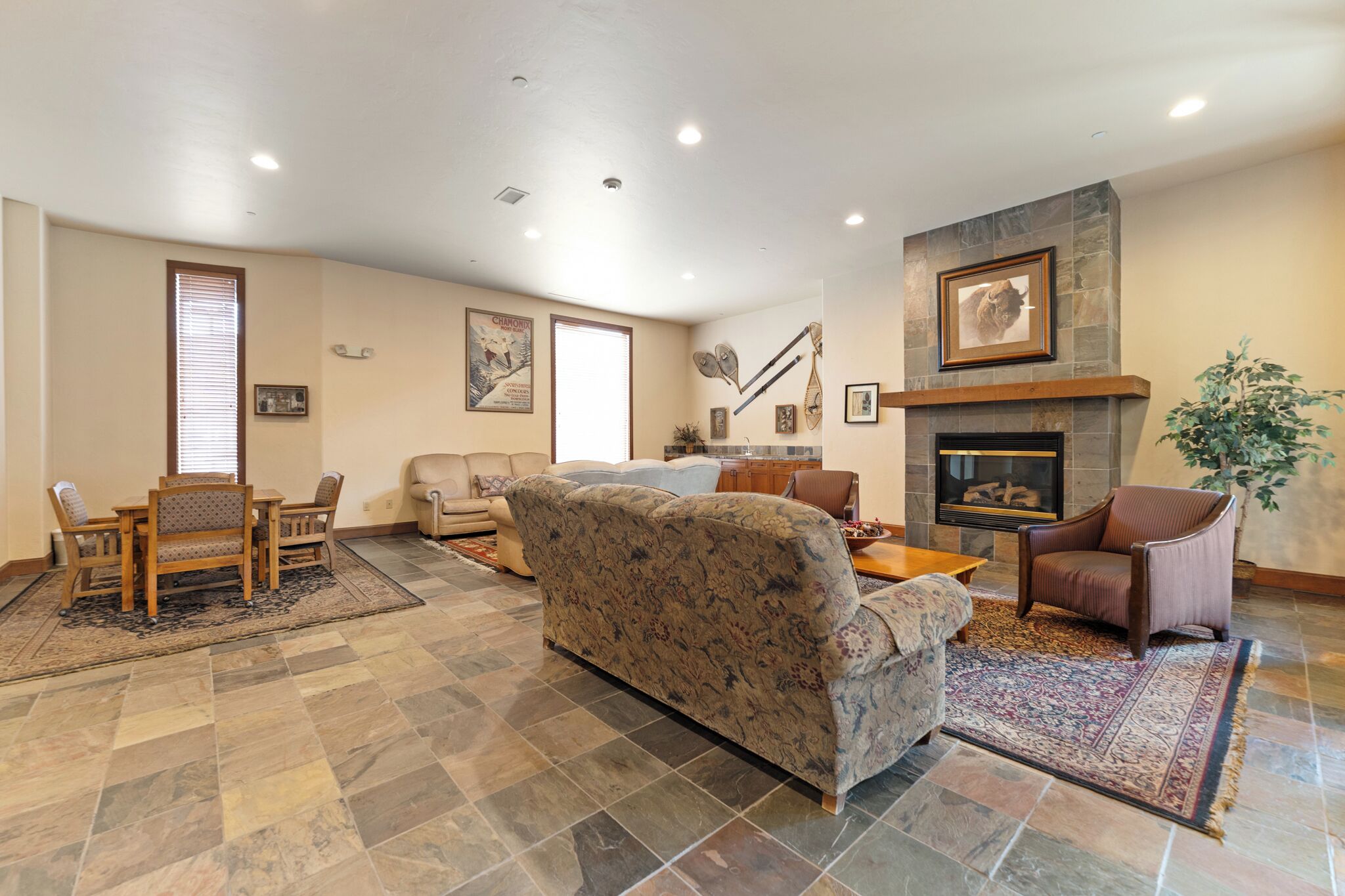 A spacious living room with a fireplace, a dining area with a table and chairs, and a large sofa.