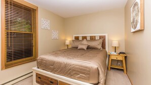 Ein Schlafzimmer mit Bett, Nachttischen, einem Fenster mit Jalousien und Wanddekoration.