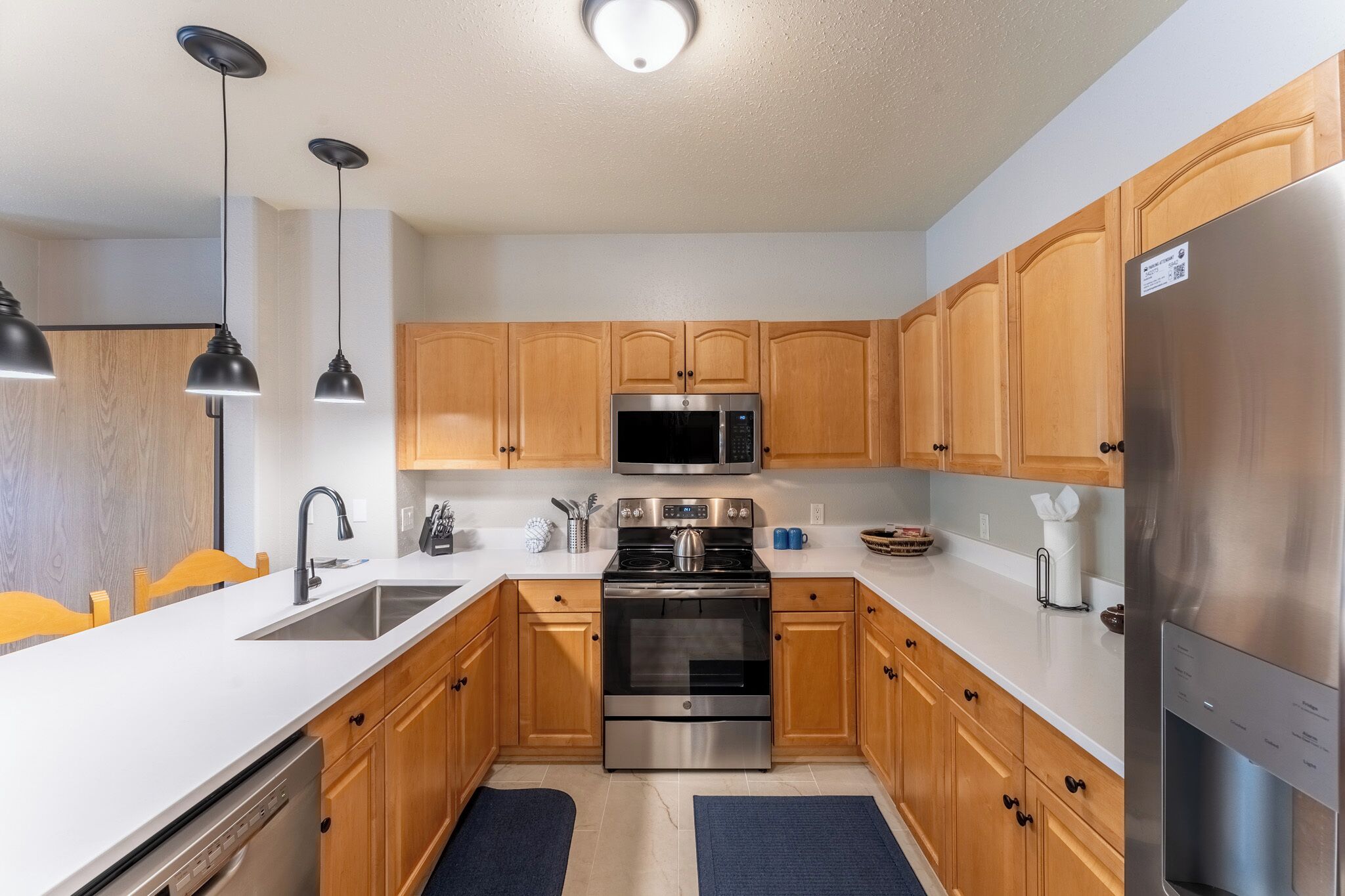 A modern kitchen with wooden cabinets, stainless steel appliances, and a white countertop.