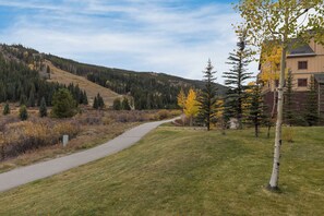 A pathway leading through a grassy area with trees and a building in the background. - Red Hawk Townhome #2349 (Keystone)