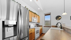 A modern kitchen with stainless steel appliances, wooden cabinets, and a built-in microwave. - Retreat on the Blue, Unit E2 : 150 (Silverthorne)