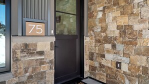 Ein Gebäudeeingang mit einer steinernen Fassade, einer schwarzen Tür und einem Schild mit der Nummer 75.