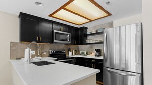 A modern kitchen with dark cabinets, stainless steel appliances, and a central island. - Greens at Copper #215 (Copper Mountain)