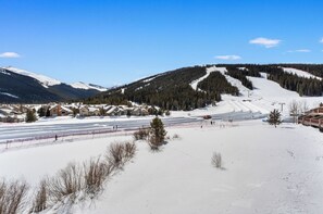 A snow-covered ski resort with multiple chalet-style buildings, a ski lift, and a clear blue sky. - Greens at Copper #215 (Copper Mountain)