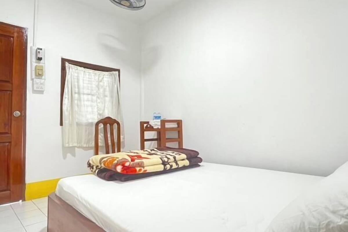 A bedroom with a bed, a chair, a window with curtains, and a door.