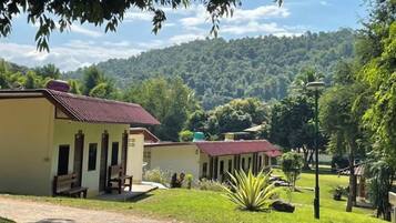 A building with a red roof, a covered outdoor seating area, and a view of a forested hill.