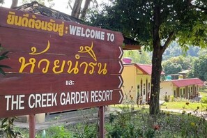 A wooden sign welcoming visitors to The Creek Garden Resort, with Thai script and English text. - The Creek Garden Resort (Mae Hong Son)