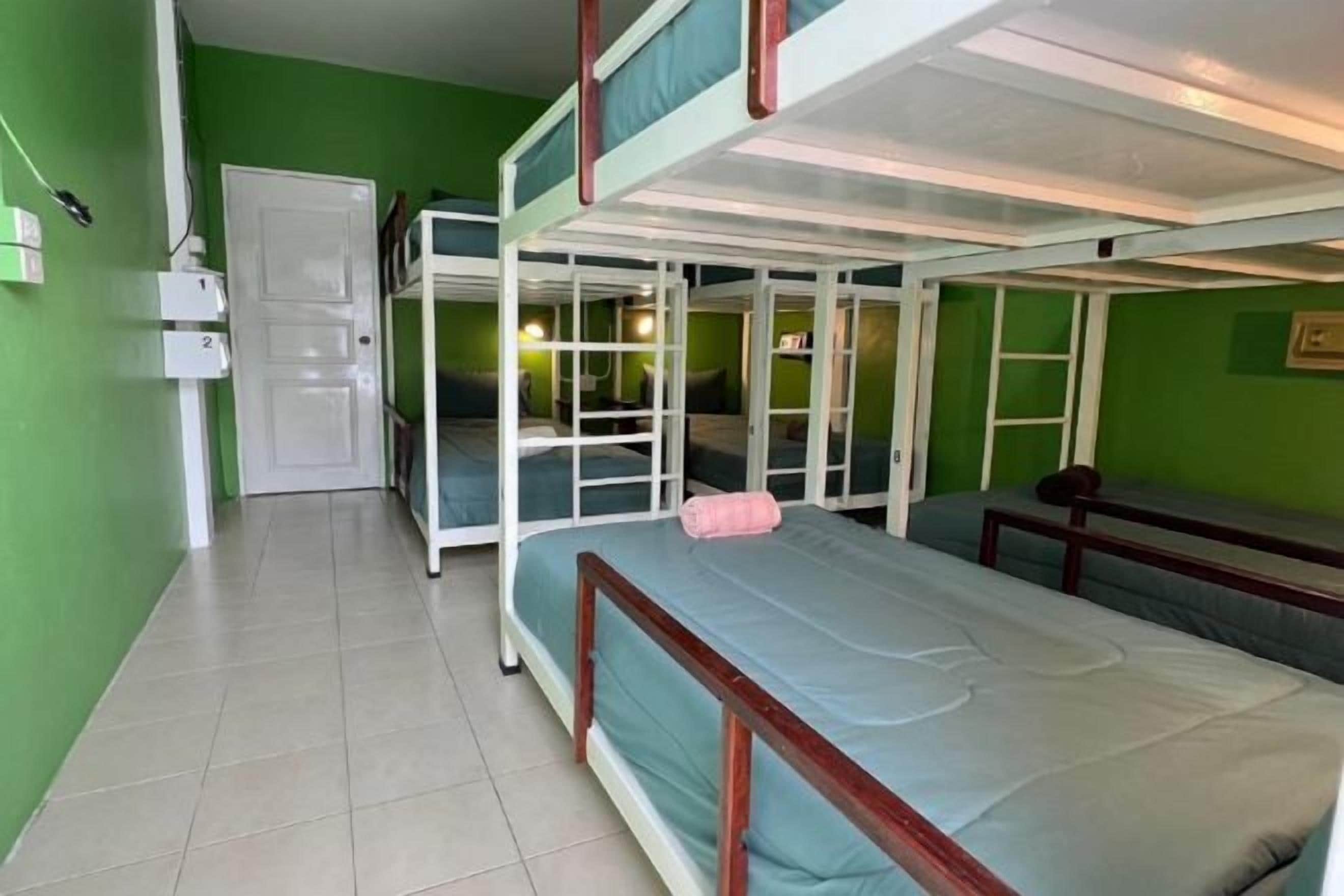 A room with bunk beds, a door, and a bench.