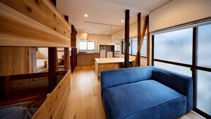 Et moderne interiør med køjesenge, en blå sofa og et køkkenområde.