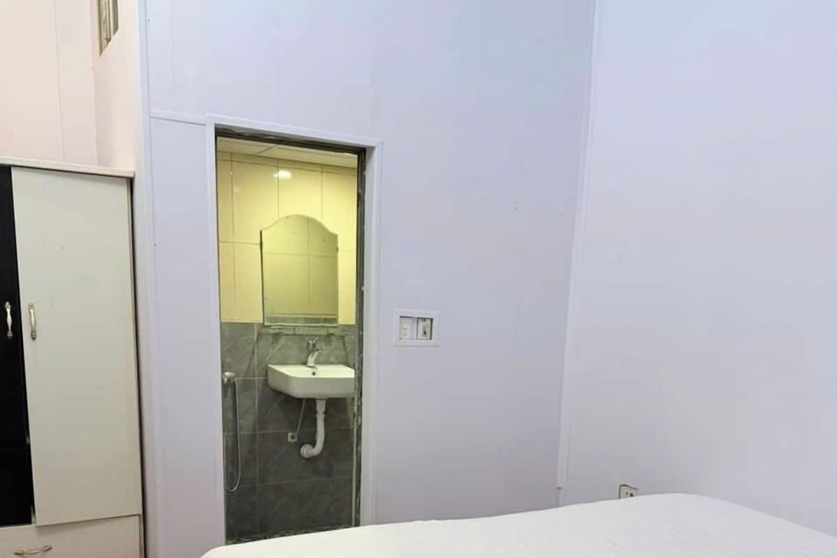 A bedroom with a bed, a wardrobe, and a bathroom visible through an open door.