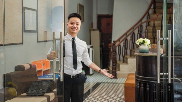 A hotel lobby with a modern design, featuring a staircase, a reception desk, and a seating area with a patterned rug. - Hanoi Old quarter Central Hotel (Hanoi)