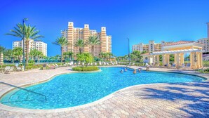 A swimming pool area with palm trees, lounge chairs, and a pavilion. - Beachfront Bliss by the Surf | Inlet #605 (New Smyrna Beach)