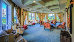 A spacious lounge with comfortable seating, large windows, and a view of the outdoors. - Beachfront Bliss by the Surf | Inlet #605 (New Smyrna Beach)
