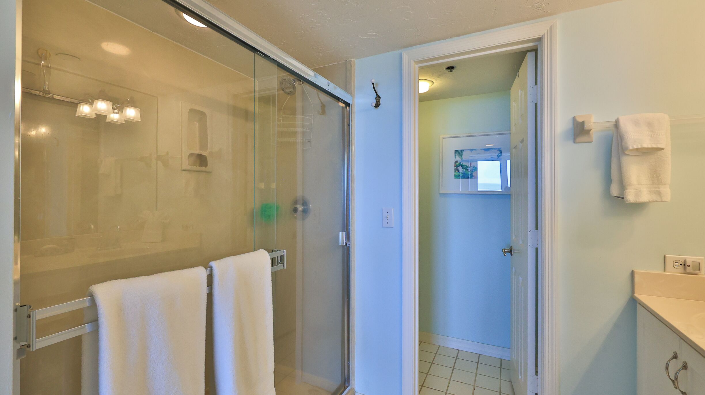 Ein modernes Badezimmer mit Duschkabine aus Glas, einem weißen Handtuchhalter und einer sichtbaren Steckdose.