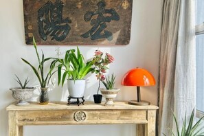 A wooden console table with potted plants and a lamp.