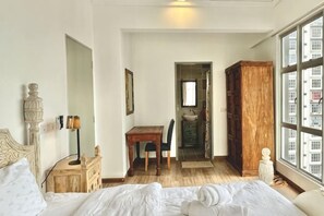 A bedroom with a bed, a desk, a chair, a wardrobe, and a window with a view of buildings. - 3BR KL Sentral L21 Modern Vintage City View (Kuala Lumpur)