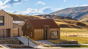A modern house with a sloped roof, large windows, and a stone foundation. - The Soho (Wānaka)