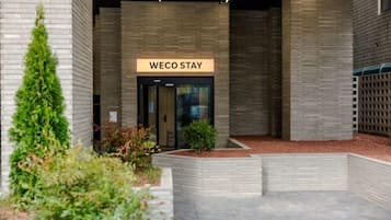 Entrada de um edifício moderno com uma placa que diz 'WECO STAY'.