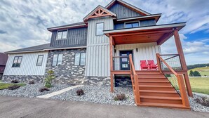 A modern two-story house with a stone facade, a wooden porch, and a number '50' sign.