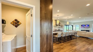 A modern kitchen with a central island, wooden flooring, and a dining area with bar stools.