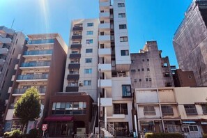 A multi-story building with balconies, a red awning, and a clear sky. - Tokyo Asakusa House (Tokyo)
