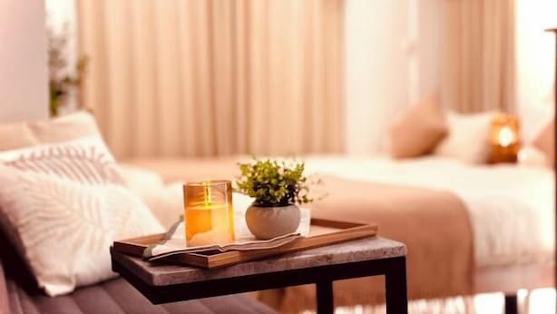 A neatly arranged tray with a candle, a small potted plant, and a book on a wooden table in a bedroom with a bed and curtains in the background. - Tokyo Asakusa House (Tokyo)
